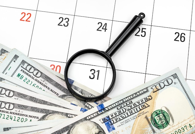 Loupe avec de l'argent sur le calendrier Se concentrer sur le dernier jour du mois Concept d'entreprise
