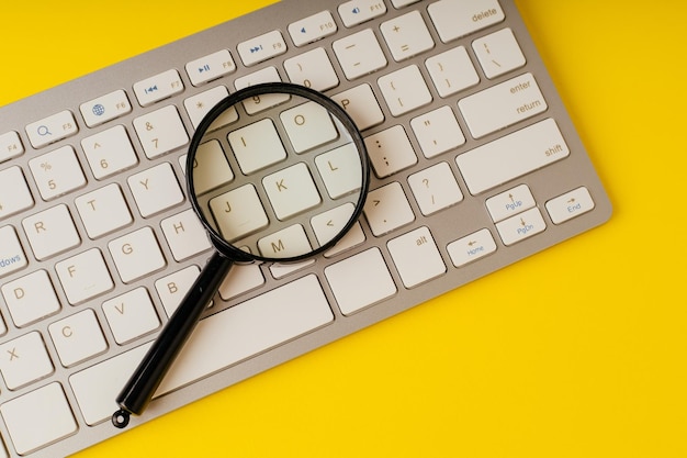 Loupe sur clavier d'ordinateur sur fond jaune