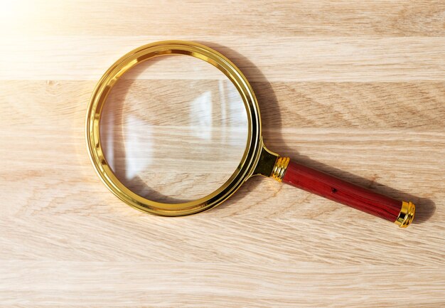 Loupe dorée sur un bureau en bois. Loupe sur fond en bois.