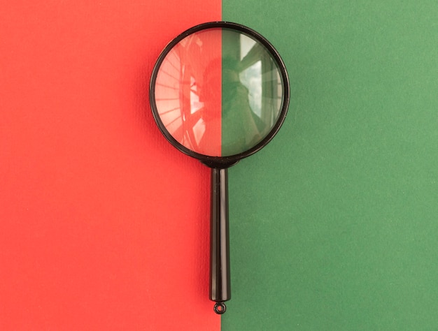 Loupe sur fond bicolore vert et rouge. Concept de recherche et de recherche.