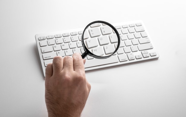 Photo loupe noire sur un clavier blanc sur un tableau blanc. concept d'entreprise.