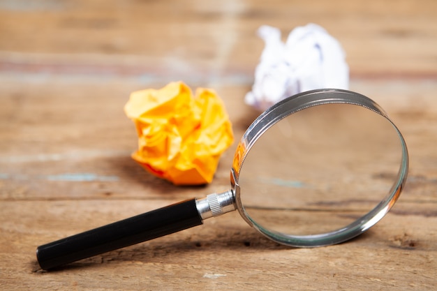 Loupe et papiers froissés sur une table en bois. recherche de concept pour une idée