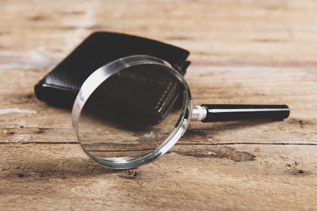 Loupe et portefeuille sur table en bois