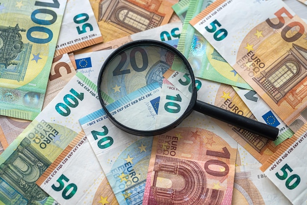La loupe se trouve sur une pile de concept d'économie d'argent en euros
