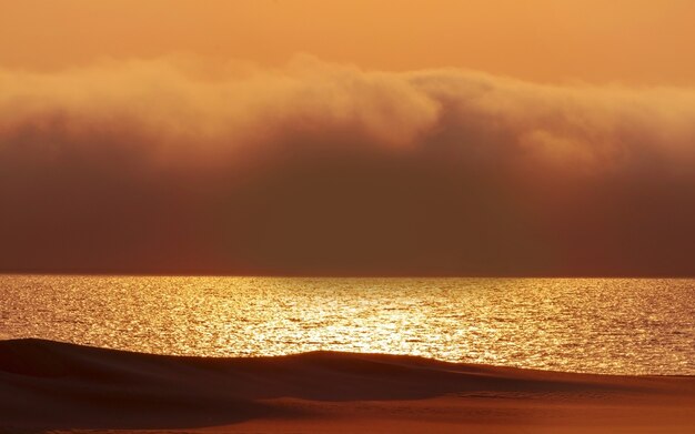 De lourds nuages dramatiques et un ciel lumineux au-dessus de l'océan Atlantique. Beau coucher de soleil sur le désert africain