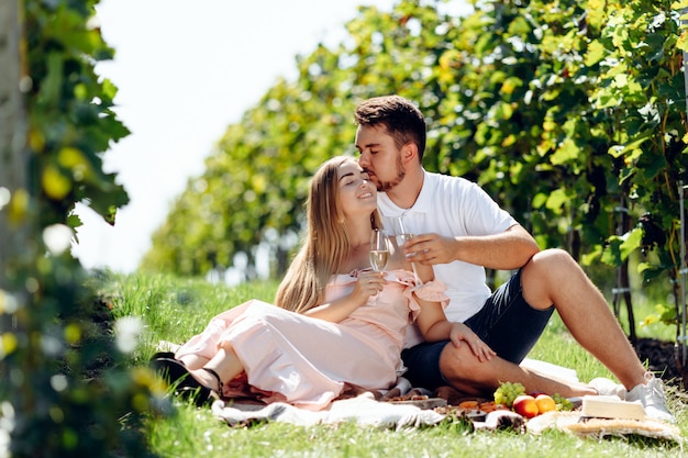 Loving jeune couple ayant pique-nique dans un vignoble.