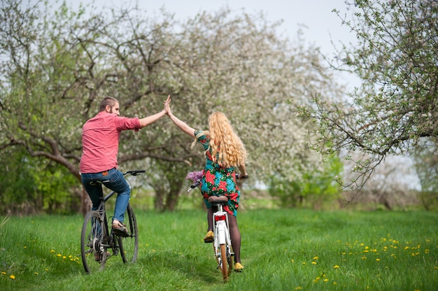 Loving jeune couple à vélo dans le jardin de printemps