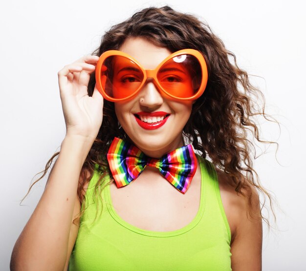 Ludique jeune femme bouclée avec des lunettes de fête.