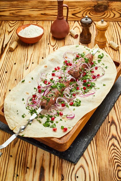 Lula kebab plat géorgien avec de la viande servie par des oignons et des légumes verts dans du pain pita