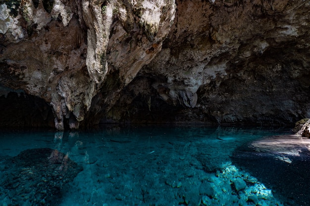 La lumière descend dans l'obscurité d'une caverne submergée avec un lac bleu