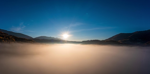 Lumière du coucher du soleil parmi les nuages au-dessus du canyon montagneux dans la brume