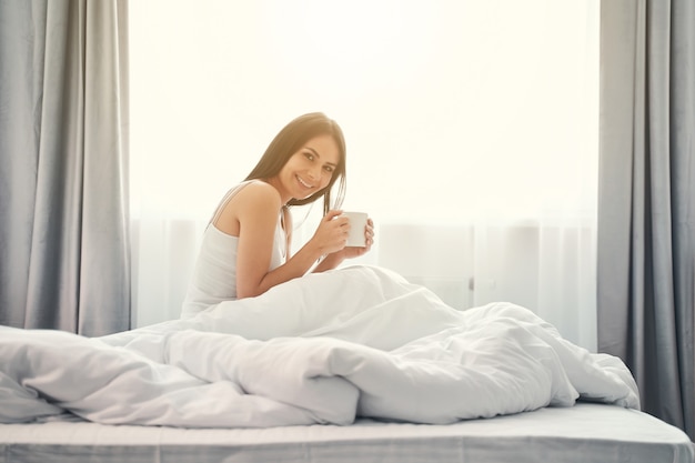 Lumière du matin. Joyeuse jeune femme gardant le sourire sur son visage tout en regardant droit devant