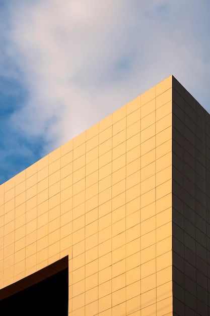 Lumière du soleil dorée sur la surface du mur de l'immeuble de bureaux moderne contre le ciel bleu nuage blanc