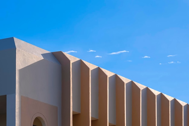 La lumière du soleil et l'ombre sur les ailettes de mur en béton la surface du parasol de la maison beige moderne contre le ciel bleu