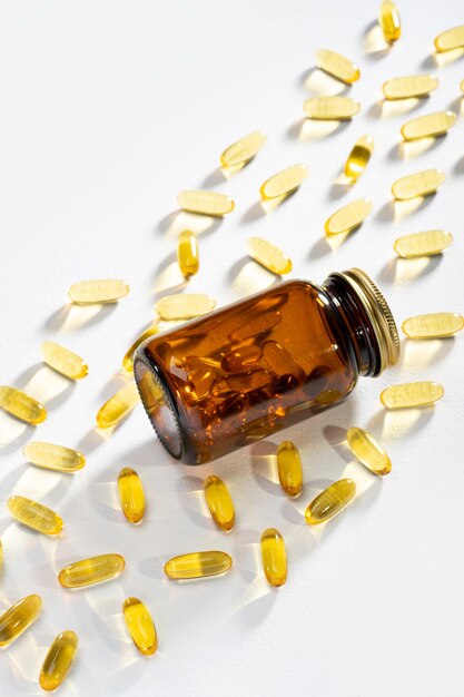 La lumière du soleil passe à travers une bouteille avec des pilules et des capsules Omega3