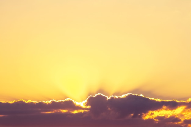 La lumière du soleil pénètre à travers les nuages sombres dans le ciel jaune, le ciel au coucher du soleil