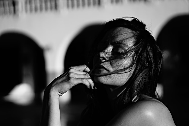 La lumière du soleil tombant sur une jeune femme avec les cheveux en désordre contre le bâtiment