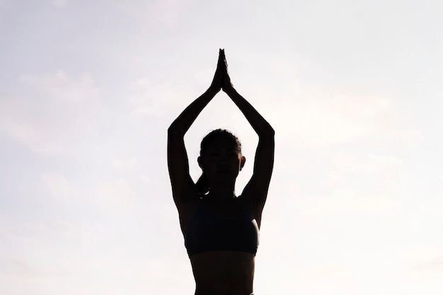 La lumière de fond d'une jeune femme faisant de la méditation au yoga