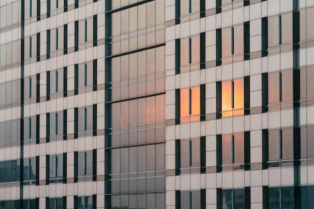 La lumière orange du coucher de soleil se reflétait sur la façade en verre et en revêtement le soir.