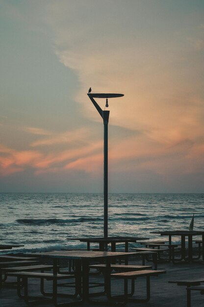 Lumière de rue par la mer contre le ciel au coucher du soleil