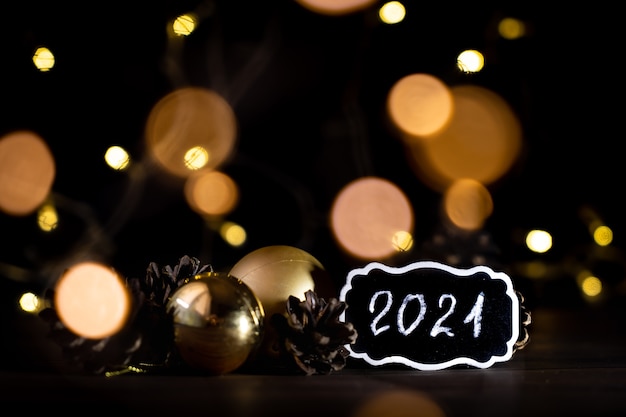 lumières floues sur fond noir avec des boules de Noël et texte 2021
