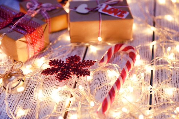Lumières de Noël dorées avec de beaux cadeaux sur une surface en bois blanche