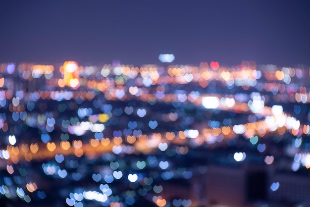 Photo des lumières orange, bleues et dorées en forme de cœur floues floutaient le bokeh. noël noir festif ou nouvel an et fond de la saint-valentin.