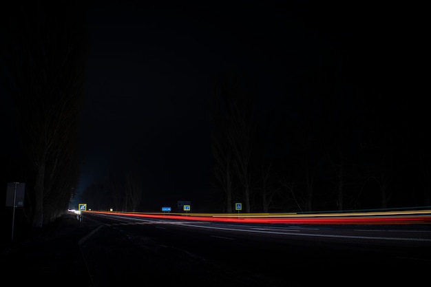 Lumières rouges et blanches des voitures qui passent. Autoroute de nuit.