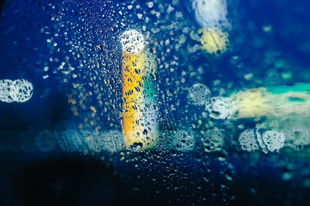 Les lumières de la ville de nuit à travers le pare-brise abstrait goutte d'eau sur les lumières en verre et la pluie.