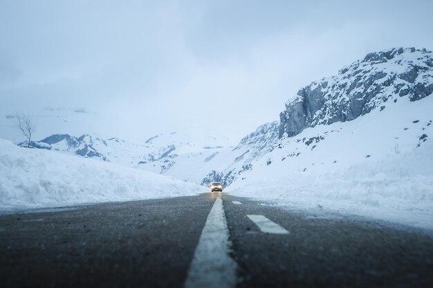 Lumières de voiture et route d'hiver dans les montagnes couvertes de neige