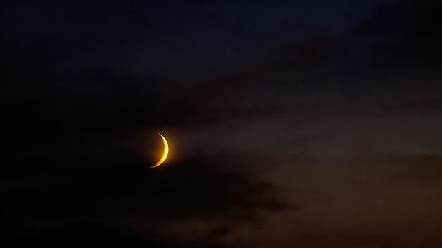 Lune croissante dans le ciel du soir sombre et nuageux Couleurs sombres de la nuit d'été