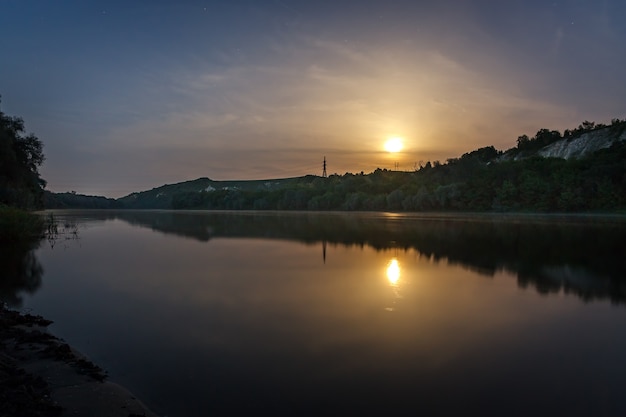 Lune dans le ciel étoilé reflétée dans la rivière