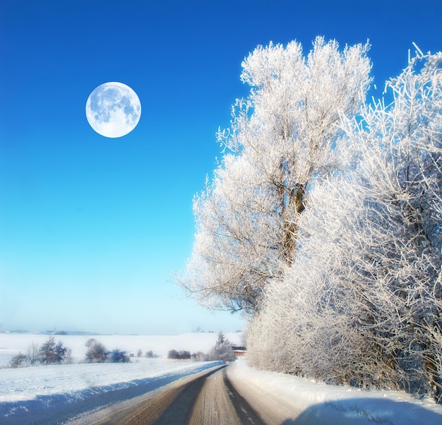 Et la lune La lune dans un paysage d'hiver Route avec de la glace sur un paysage d'hiver à midi La Lune brille à travers des nuages clairs