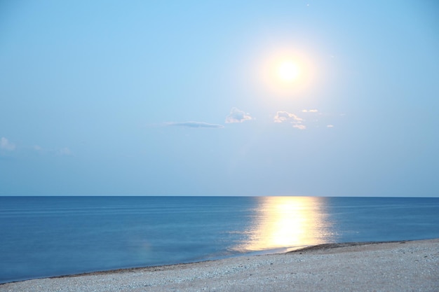 Une lune avec reflet au bord de la mer sur fond de nature