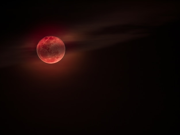 Lune de sang ou lune rouge avec des nuages ​​sur le ciel sombre