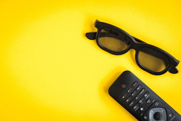 Lunettes 3D avec télécommande TV sur jaune.