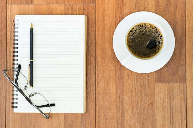 Lunettes et bloc-notes avec tasse de café sur terrasse en bois