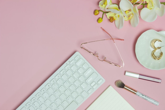 Des lunettes de clavier et des fleurs sur le fond rose