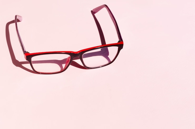 Photo lunettes sur fond rose avec des ombres sous la lumière naturelle