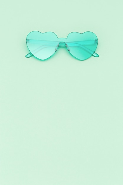 Lunettes en forme de coeur élégant sur fond de couleur vert menthe avec espace copie. Belles lunettes de soleil tendance. Concept de mode d'été.