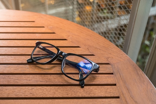 Lunettes de lecture noires sur la table en bois