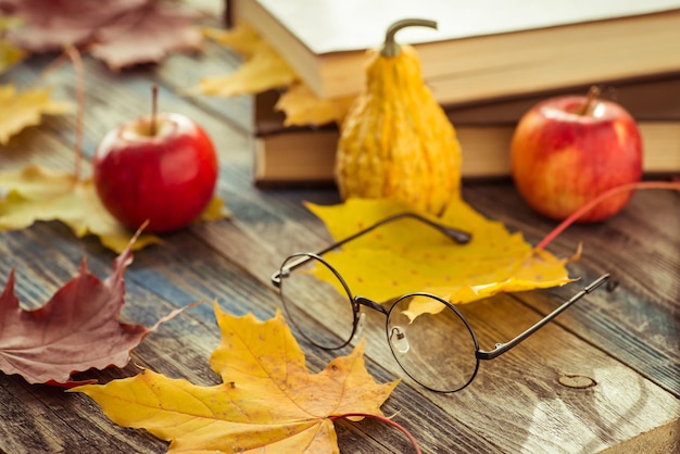 Lunettes avec livre et feuilles d'automne sur la table