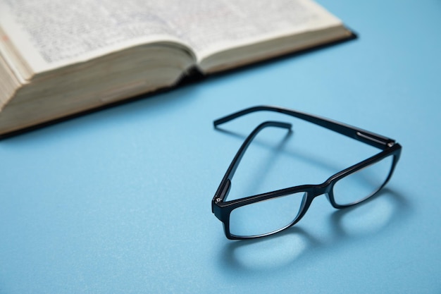 Lunettes et livre sur le fond bleu