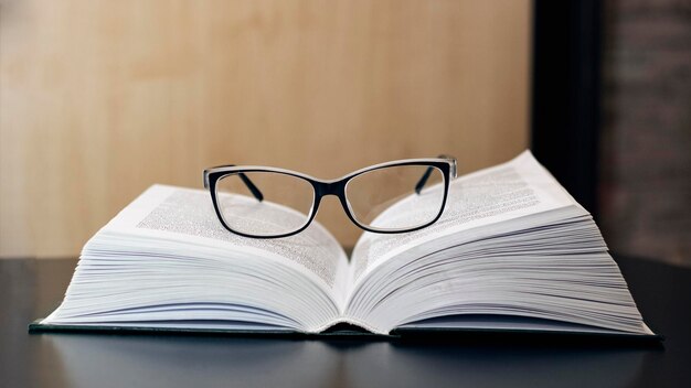 Lunettes sur livre ouvert sur table en bois