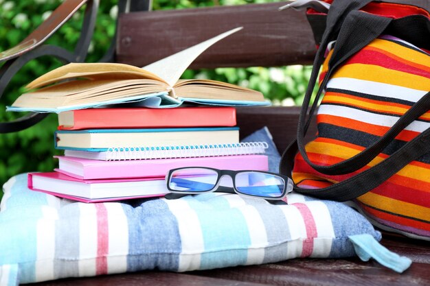 Photo lunettes de livres et sac sur banc à l'extérieur