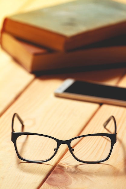 Lunettes, livres et téléphone portable sur une table en bois