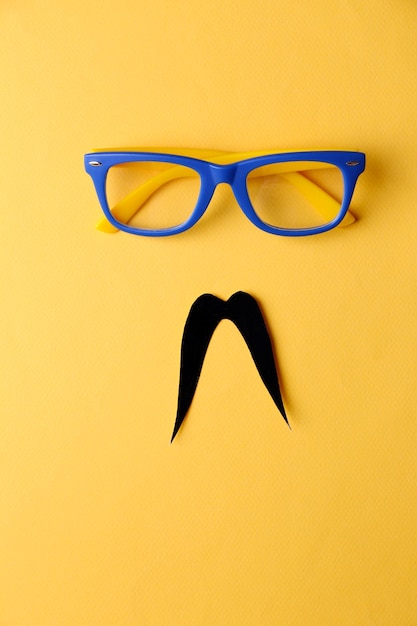 Photo lunettes et moustache formant le visage de l'homme sur fond jaune