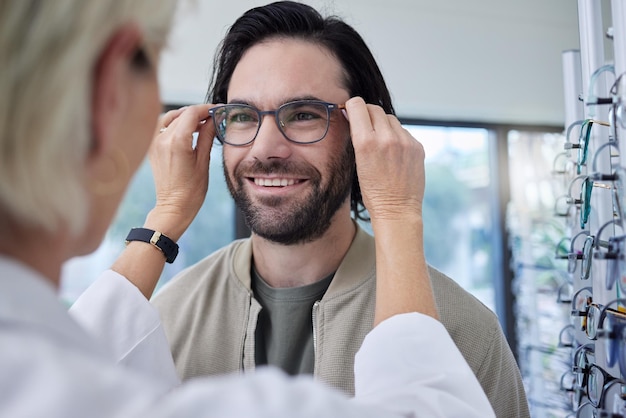 Lunettes d'opticien et homme heureux en magasin pour la vision et le choix des montures Optométriste du visage du client et lentilles pour les tests de soins oculaires conseil en soins de santé ou services de magasin de détail pour le bien-être