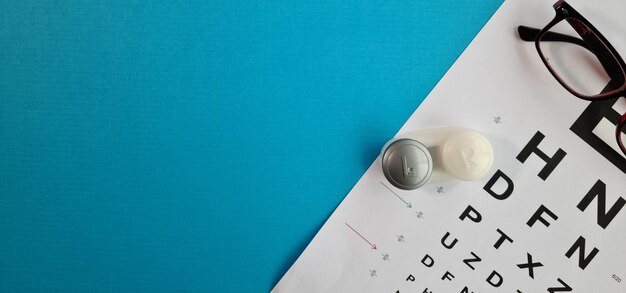 Lunettes optiques et lentilles de contact souples et une table ophtalmique sur fond bleu