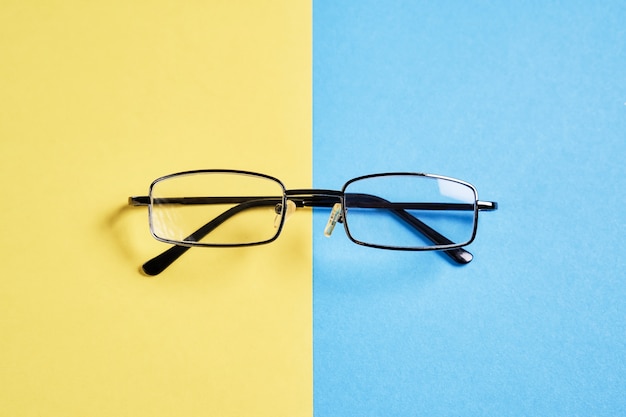 Des lunettes placées sur un fond jaune et bleu pastel divisent les moitiés.